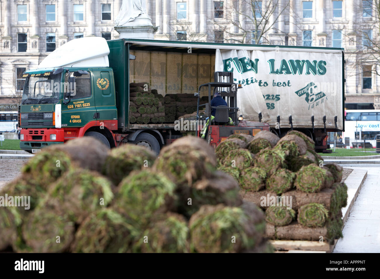 forklift truck operator unloads pallets of rolls of turf from delivery
