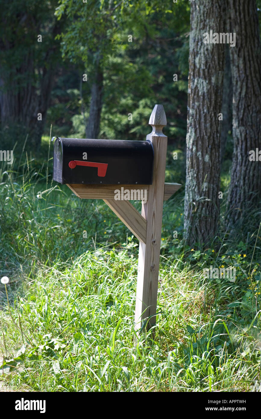 black mailbox in grass at edge of forest rural America Stock Photo