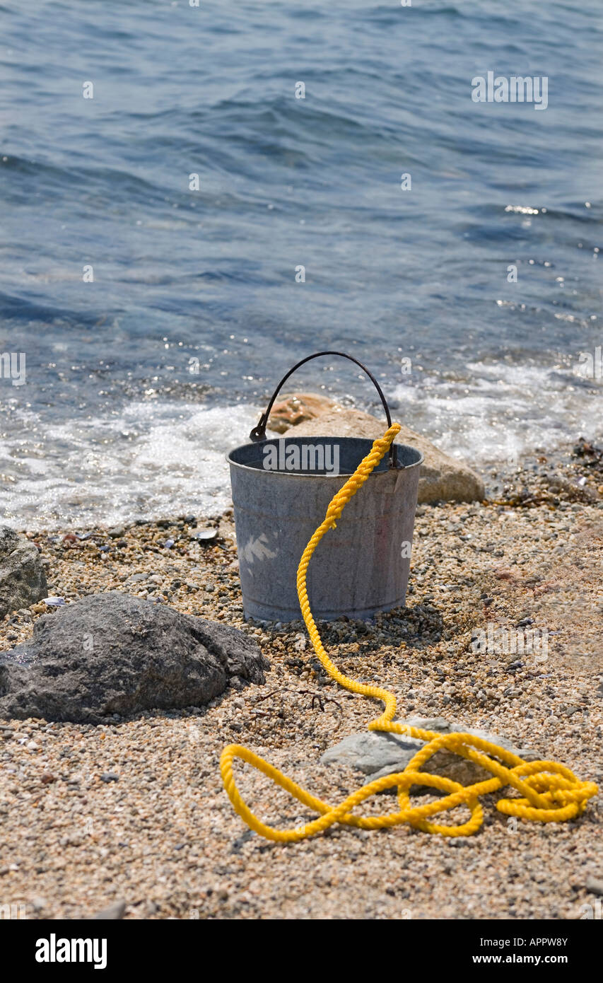 metal bucket or pail with yellow rope attached sits on beach next to