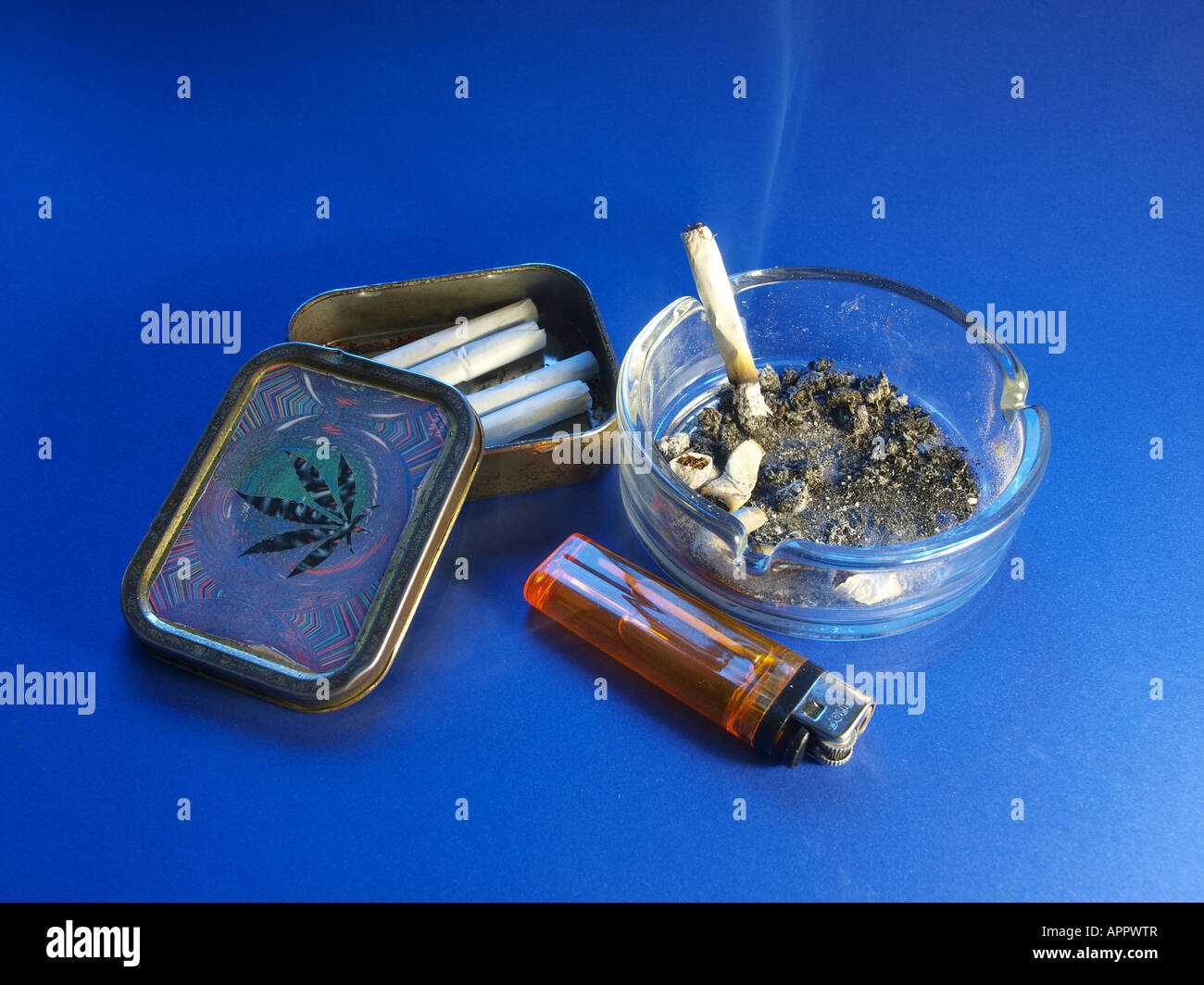 Ashtray with burning cigarette, lighter and cigarette box with cannabis