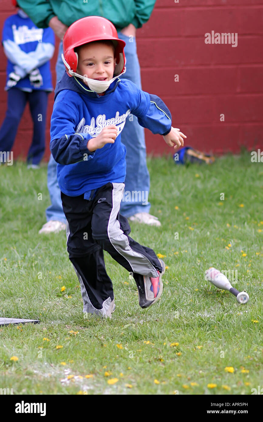 A boy running to first base after he hit the baseball off of the tee