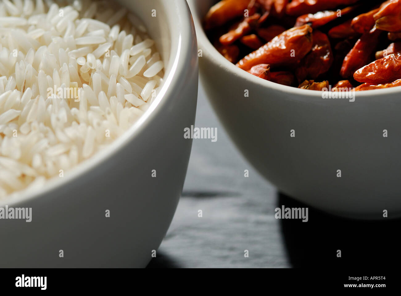bowls of indian basmati rice and dried chilli peppers Stock Photo
