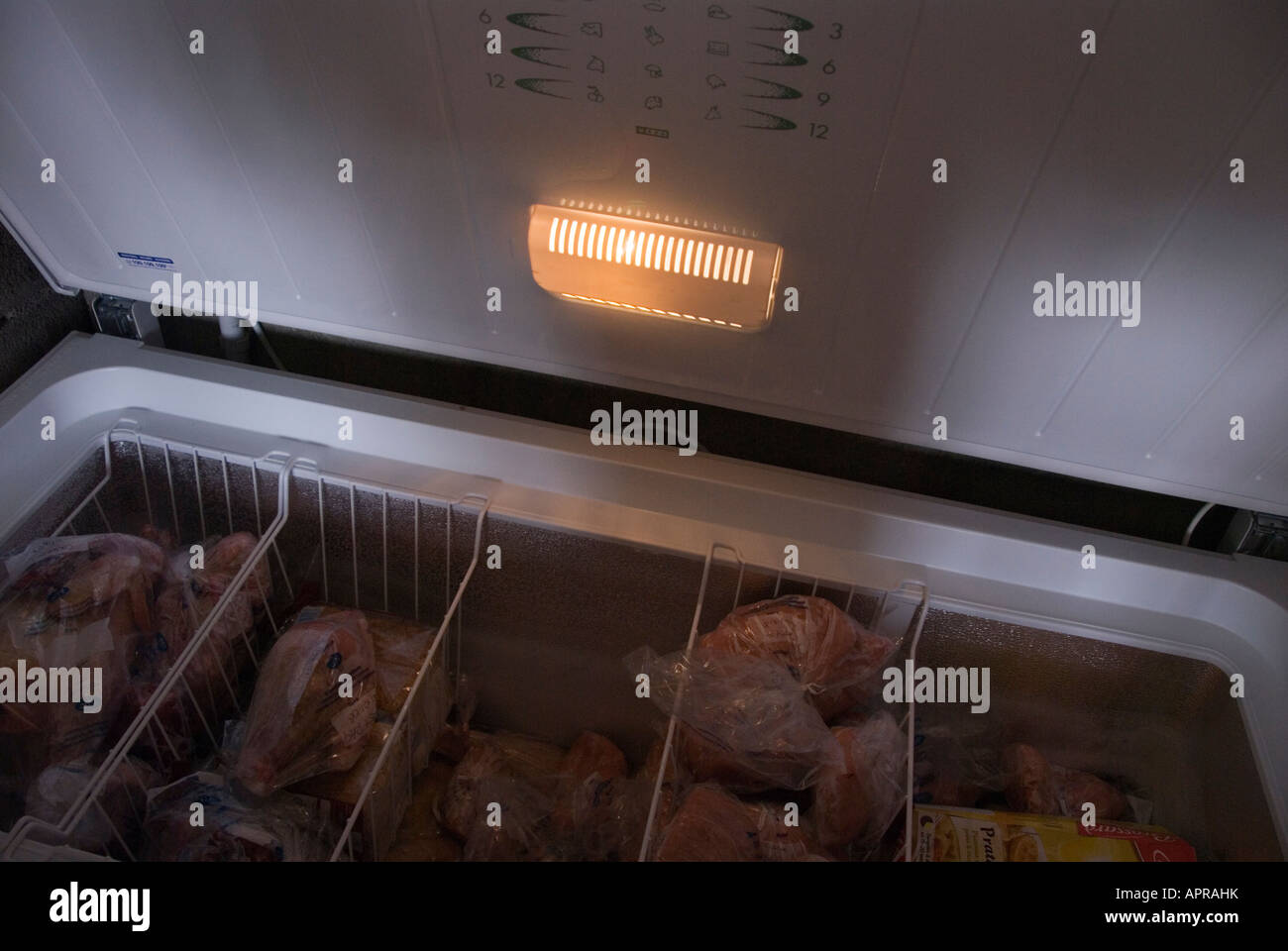 Image of a chest freezer with the lid open and lit only by the light on the lid of the freezer Stock Photo