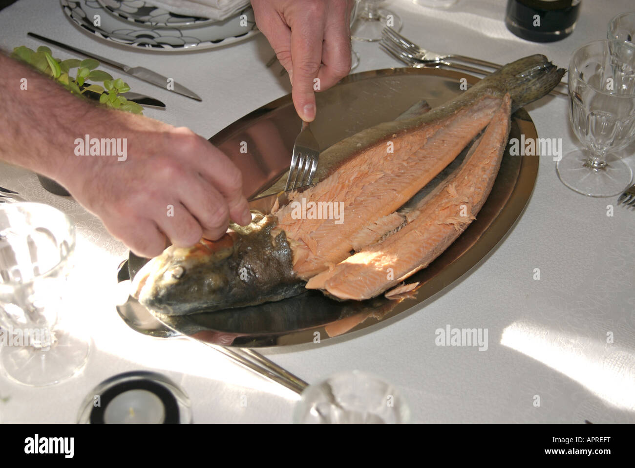 Carving / filleting a whole cooked trout fish at the dining table Stock Photo