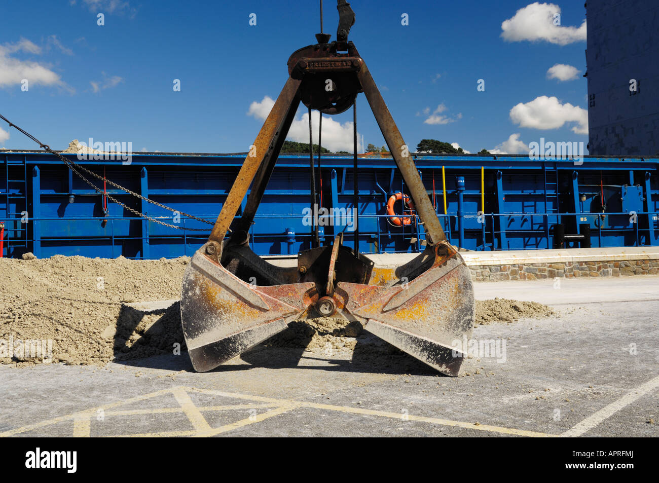 A clamshell bucket being used on a mobile crane to load aggregate onto a cargo ship on the quayside at Bideford Harbour, Devon. Stock Photo