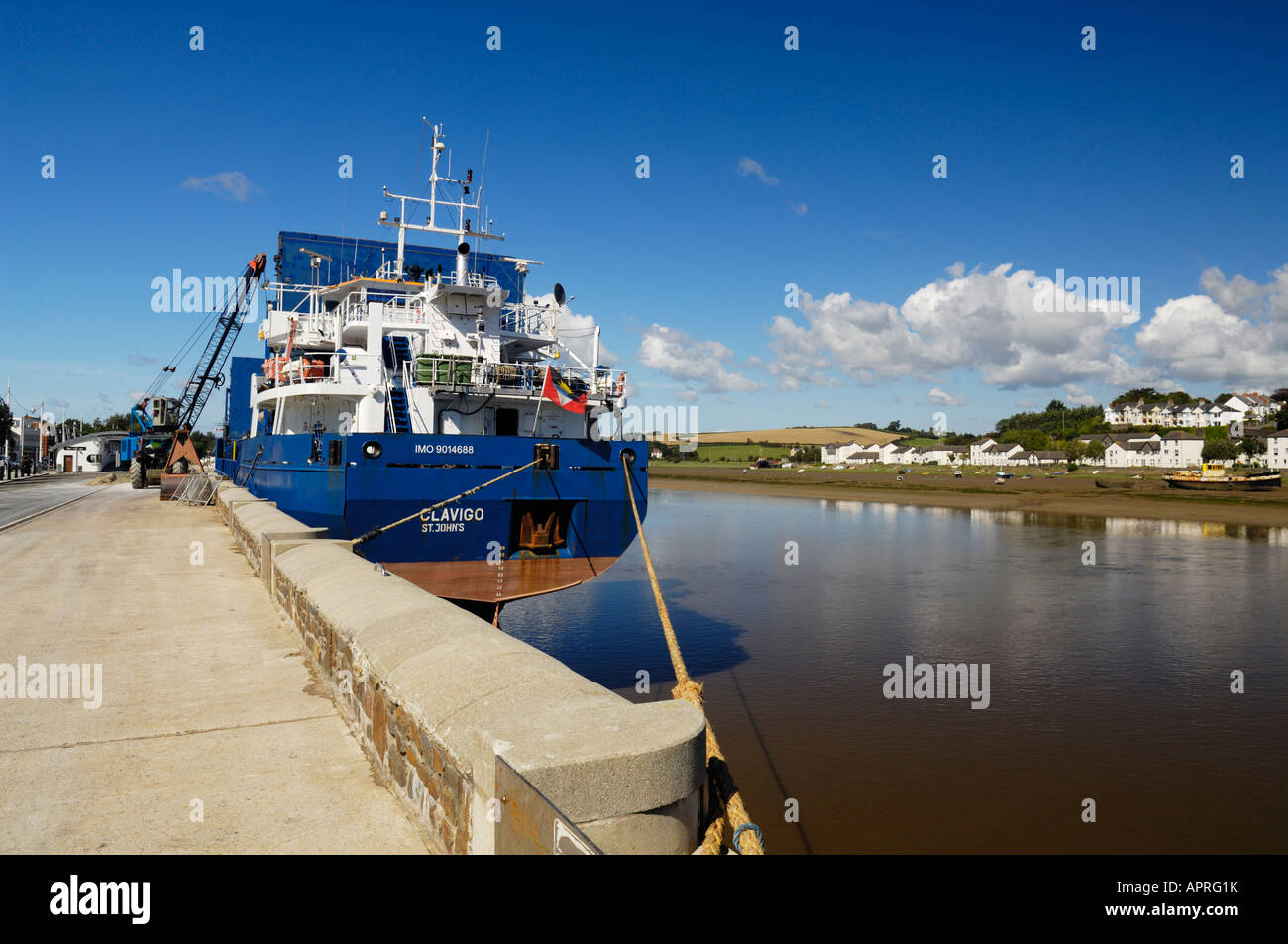 A cargo ship being loaded with aggregate by a crane on the quayside at