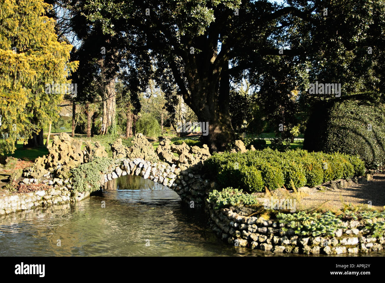 Ornamental stone bridge over stream in winter at West Dean Gardens, West Sussex, England Stock Photo