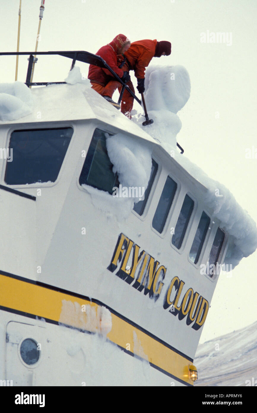 crew on a commercial ground fishing vessel break off accumulated ice Akutan Alaska Stock Photo