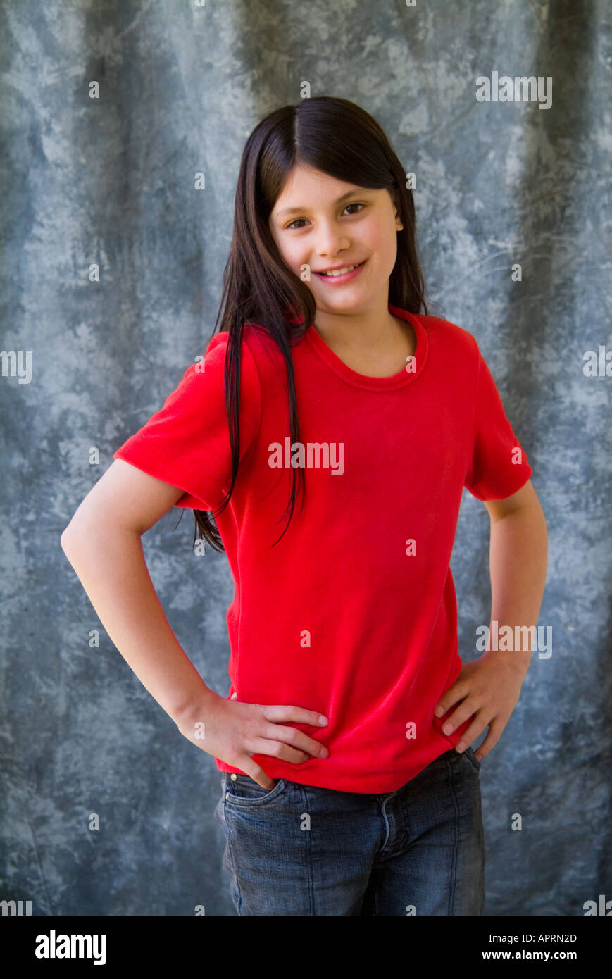 Happy young preteen girl in red tshirt on grey background looking to