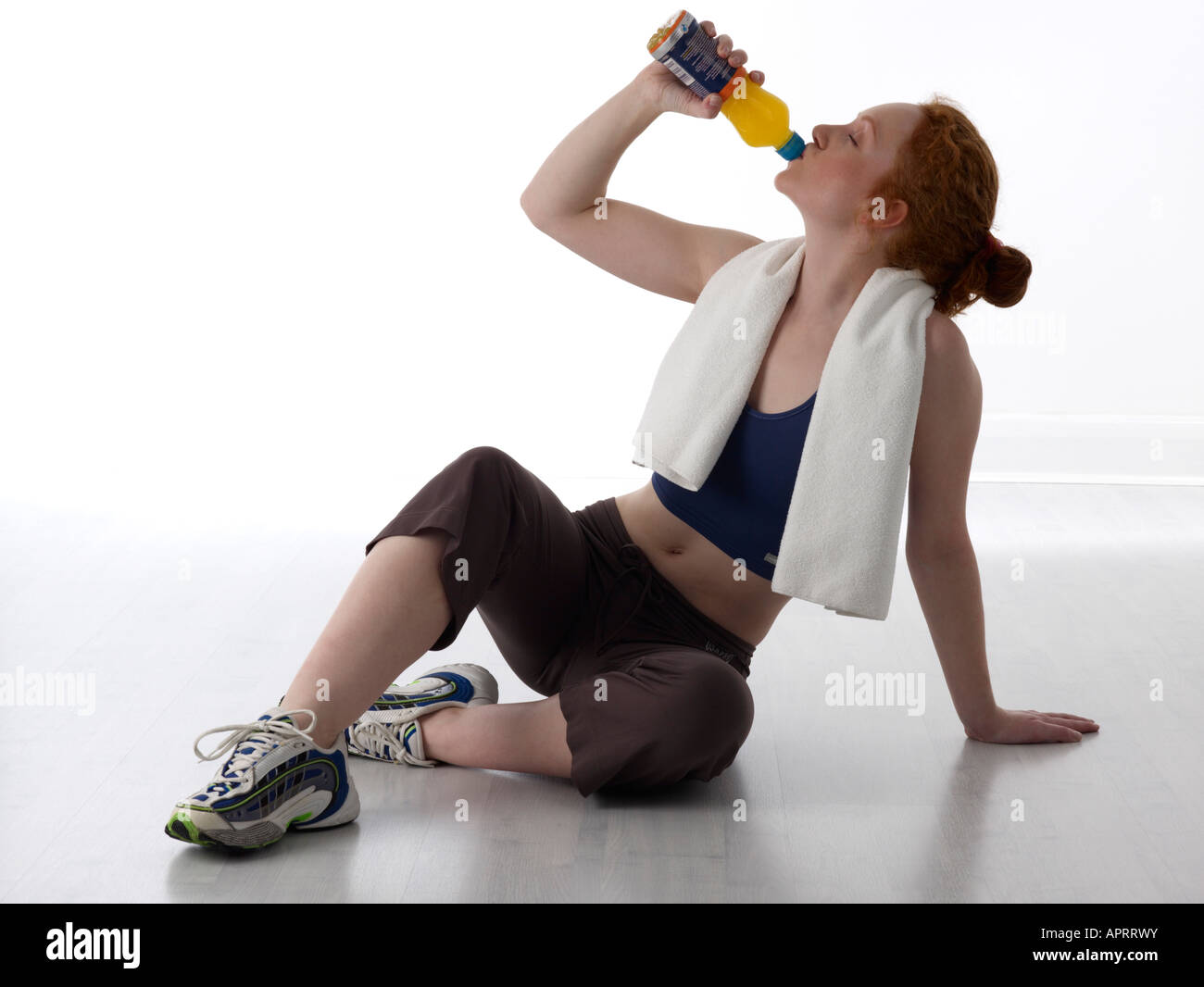 Young woman resting with sports drink after workout in a gym Stock