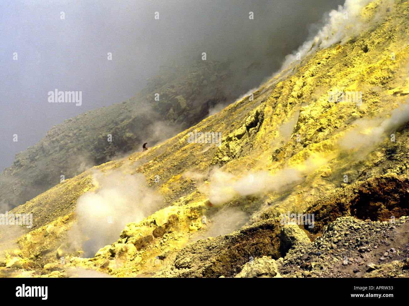 Man collecting sulfur from the side of a volcano, Java, Indonesia Stock Photo
