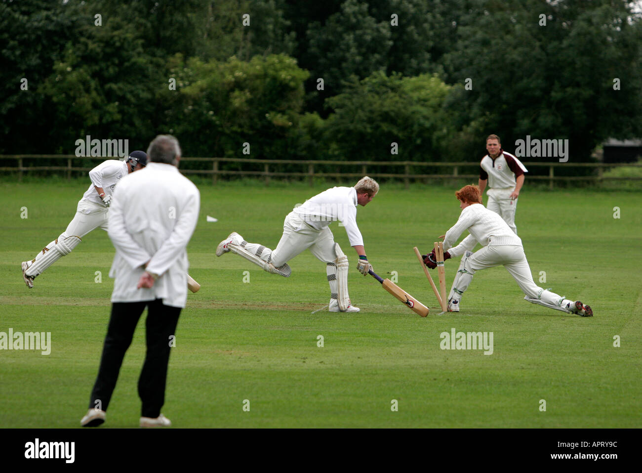 Village cricket match in progress umpire watches as batsman runs out his partner Stock Photo