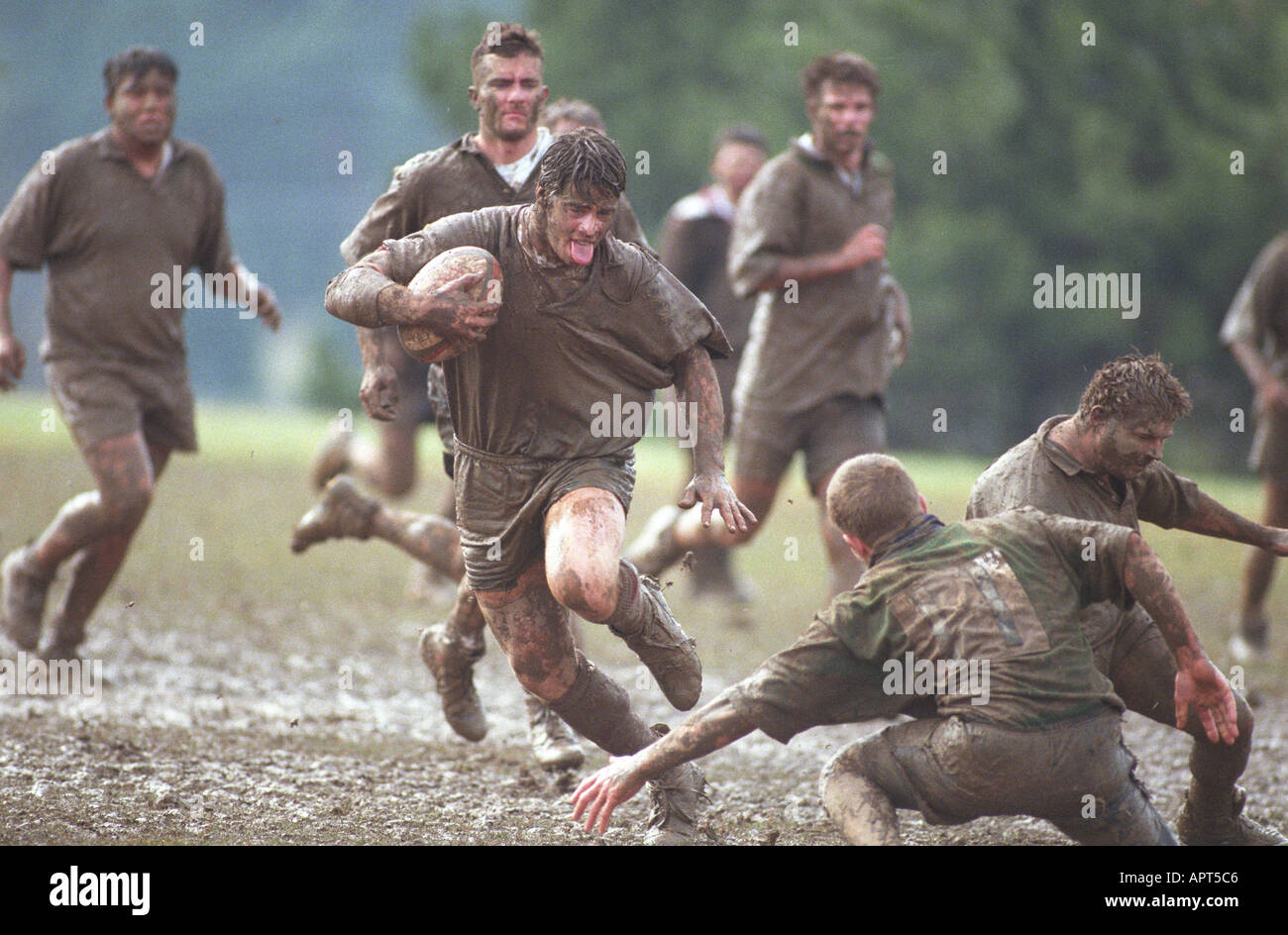 Muddy rugby player running in mud with ball. competition winning sports males winner Stock Photo
