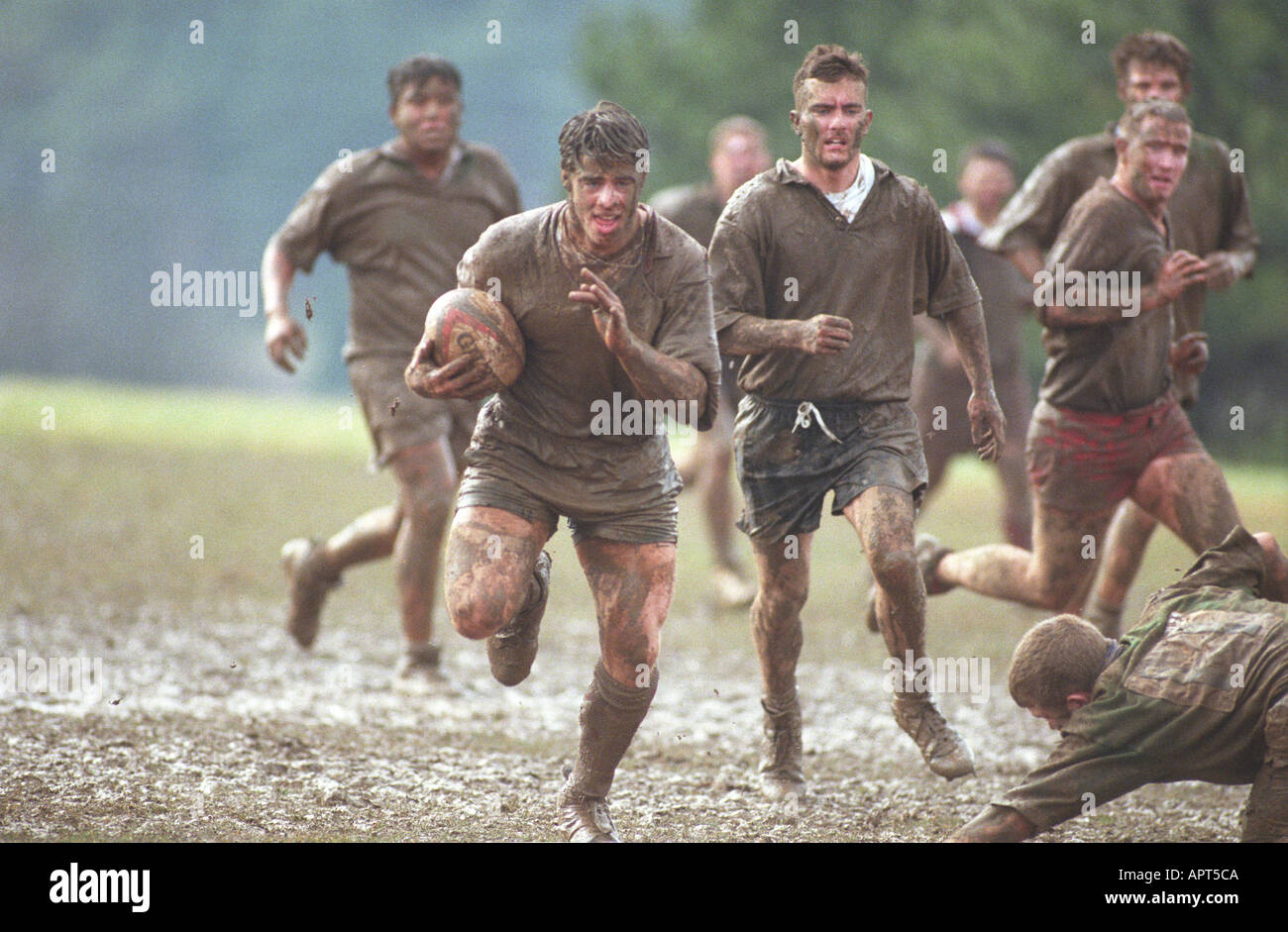 Muddy rugby player running in mud with ball. competition winning sports males winner Stock Photo