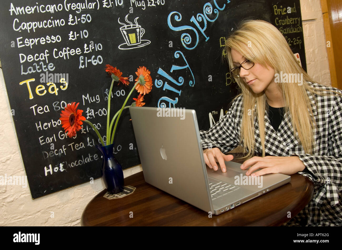 young adult woman using a laptop computer in an internet cafe Stock ...