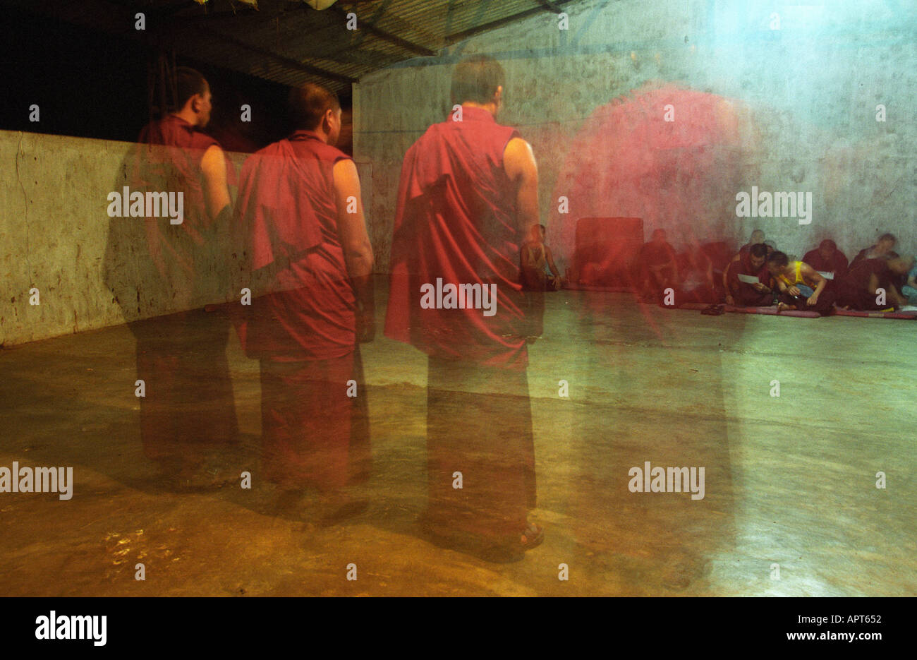 A row of Tibetan Buddhist monks are ghosted as they practice for a performance India buddhism religion eating drinking asia chanting traditional tradition indoors night blurred , Stock Photo