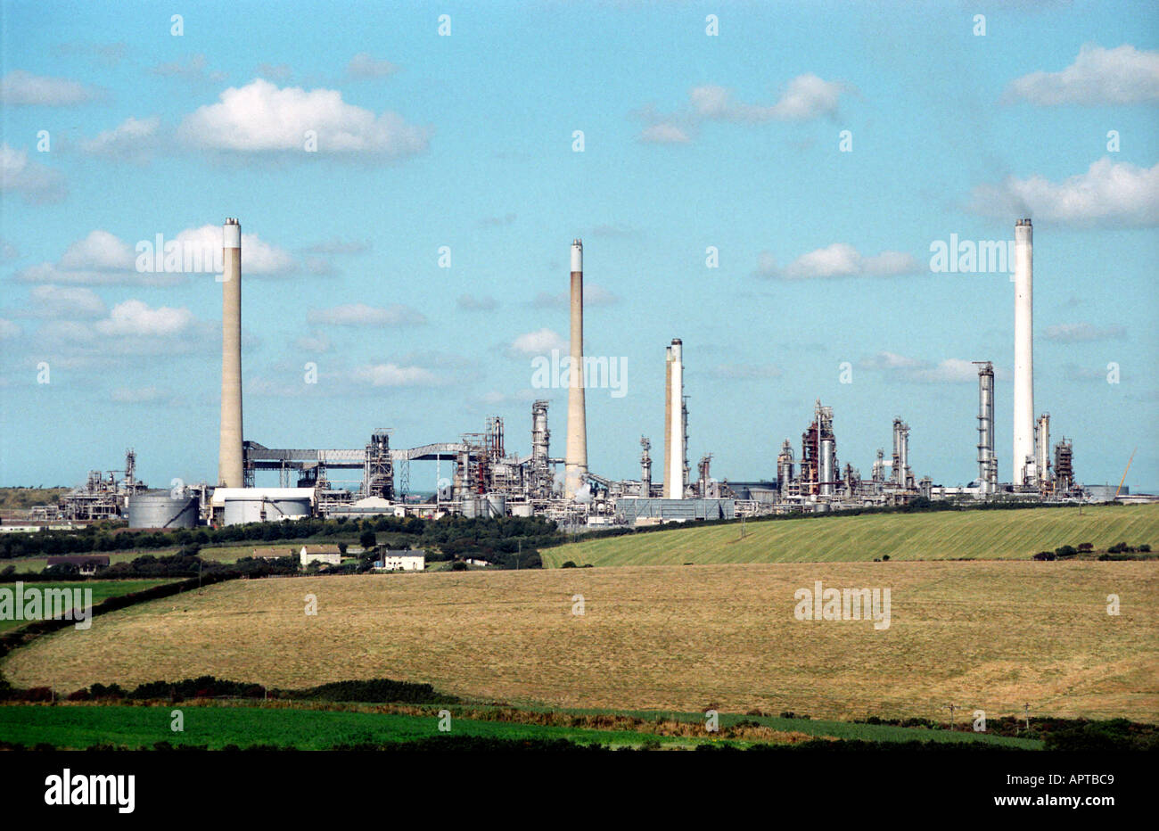 The church and village of Rhoscrowther dwarfed by the Milford Haven oil refinery Stock Photo