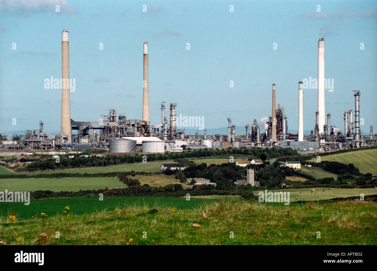 The church and village of Rhoscrowther dwarfed by the Milford Haven oil refinery Stock Photo