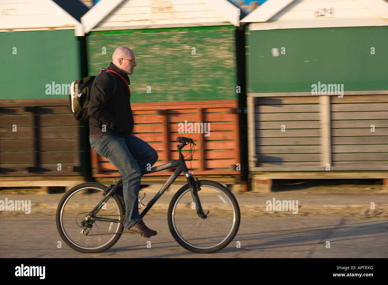 Shaven headed man riding mountain bike with no hands along