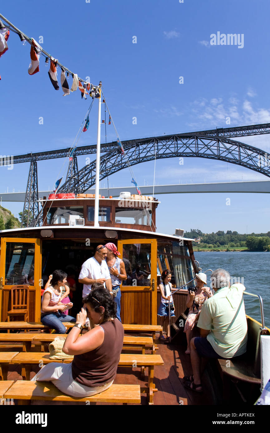 Cruise in the Douro River at Porto (Portugal) using an adapted Rabelo Boat. Maria Pia (Eiffel) and S. João bridges seen in back. Stock Photo