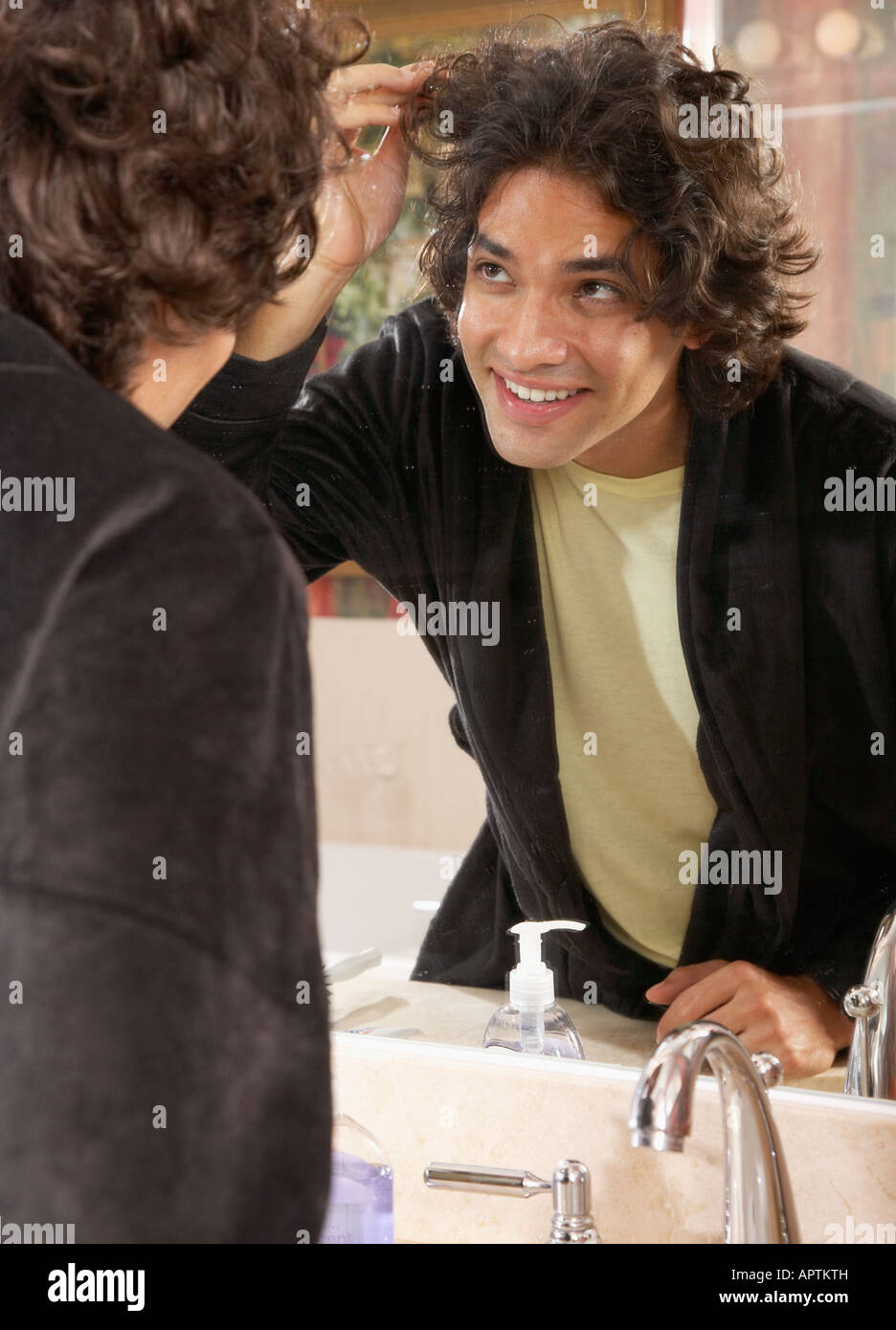 Hispanic man looking in bathroom mirror Stock Photo