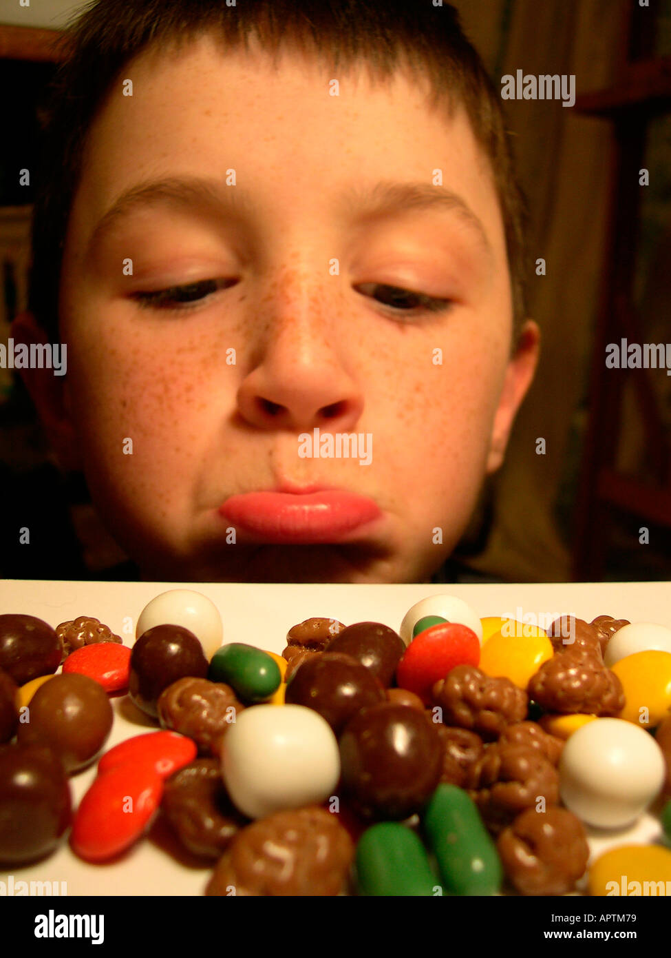 an 11 year old boy sulking at a pile of sweets model rel Stock Photo