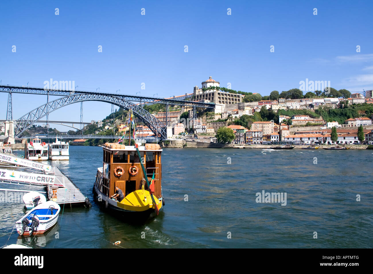 Boat used to make cruises in the Douro River at Porto (Portugal) using an adapted Rabelo Boat. D. Luis I bridge seen in back. Stock Photo