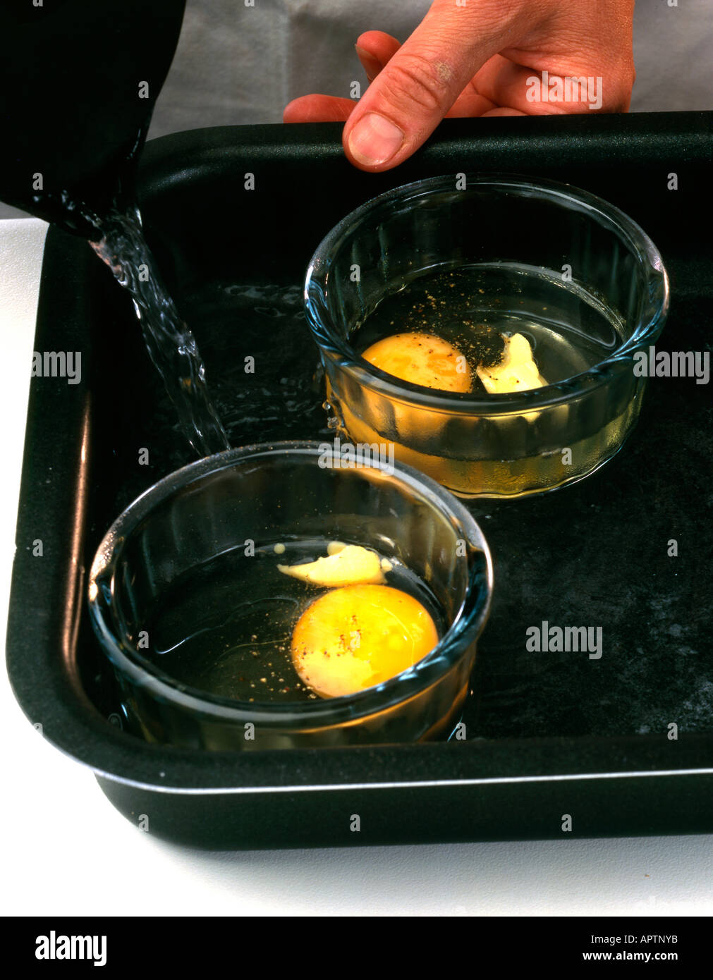 Coddling eggs in glass ramekins in roasting tin and pouring in boiling