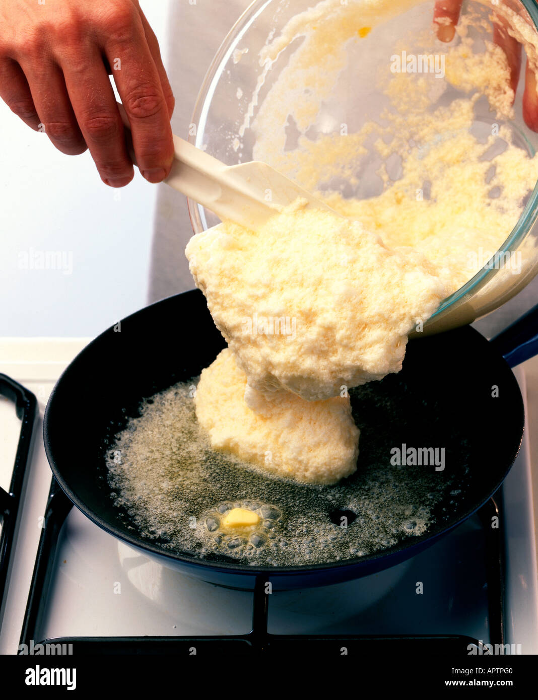 Making souffle omelette - pouring the mixture into the hot butter in the large frying pan Stock Photo