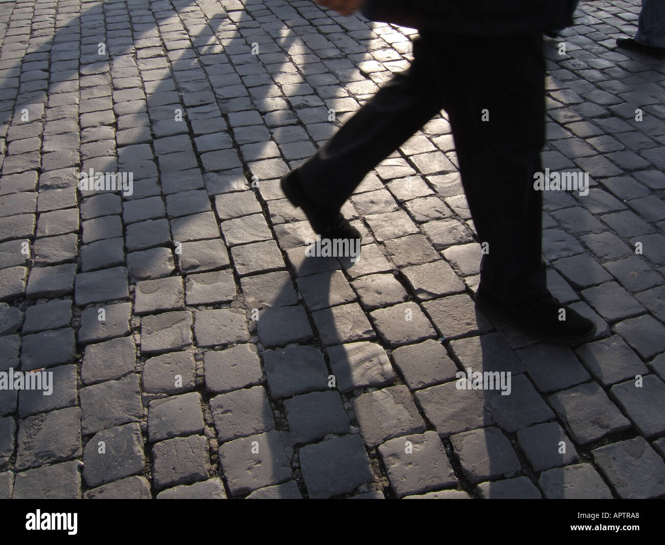 shadow of man walking on cobbled street Stock Photo - Alamy