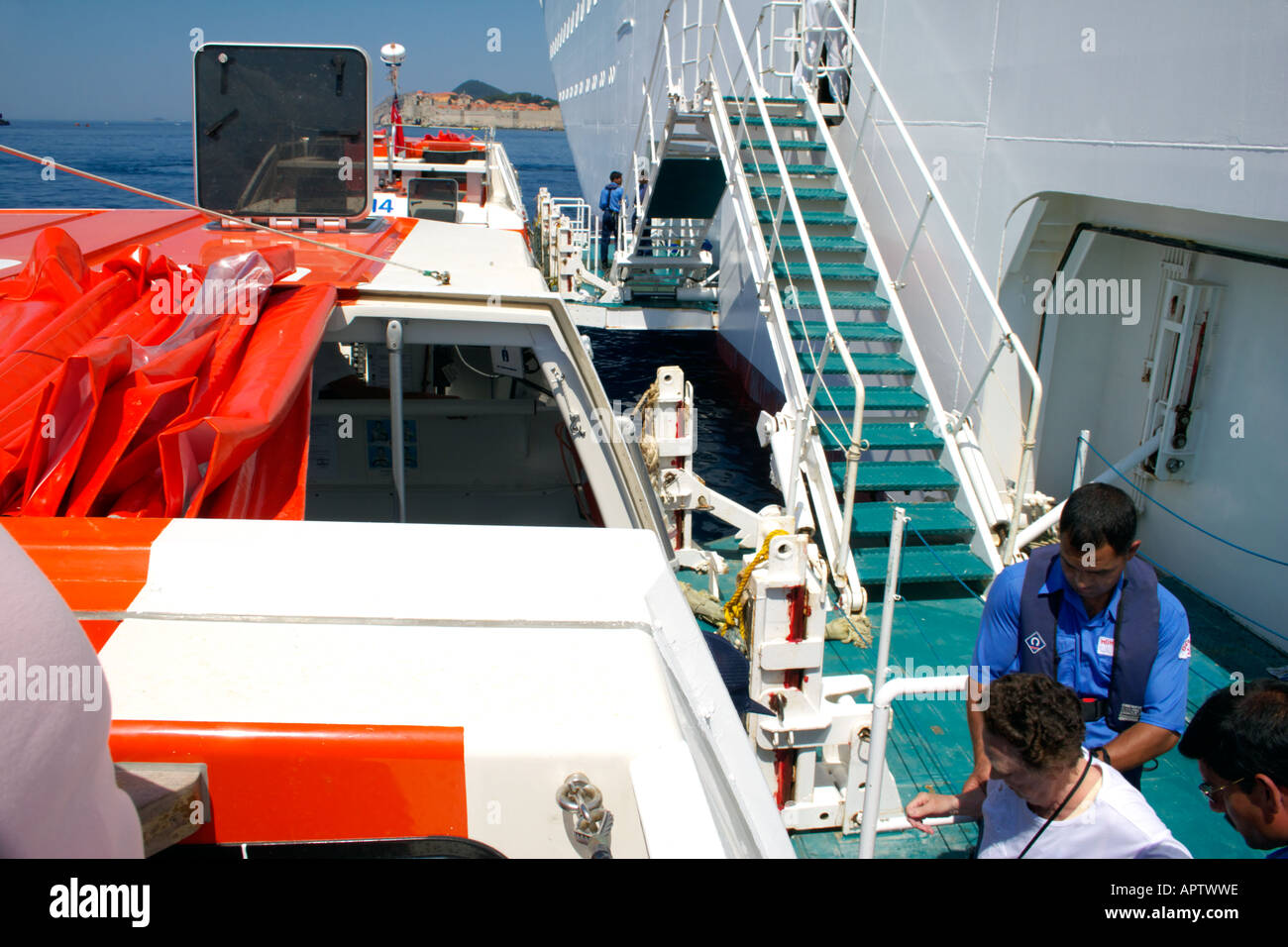Cruse ship crew help elderly female passenger to board lifeboat Stock Photo