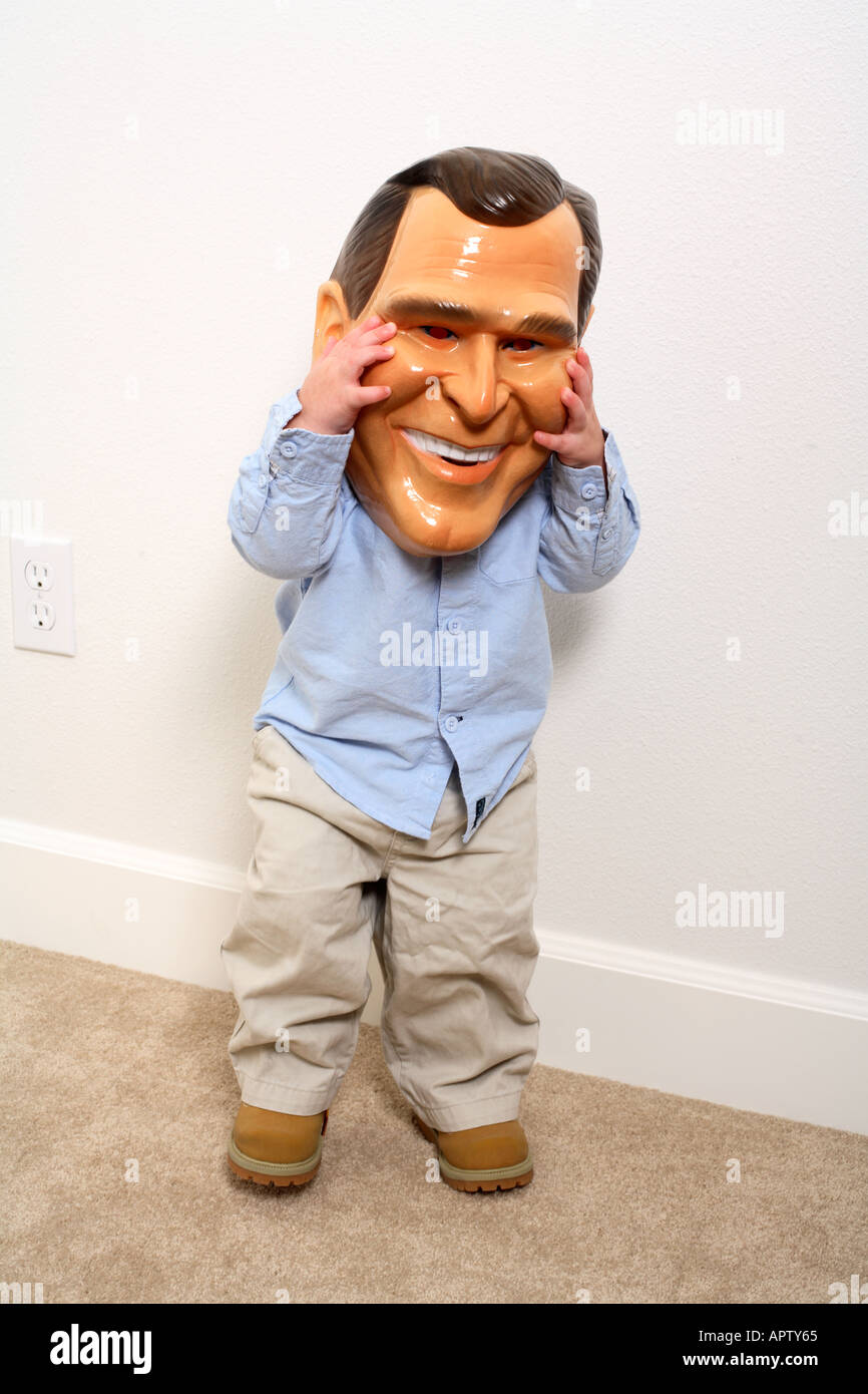 Toddler holding President George W. Bush mask up over face. Stock Photo