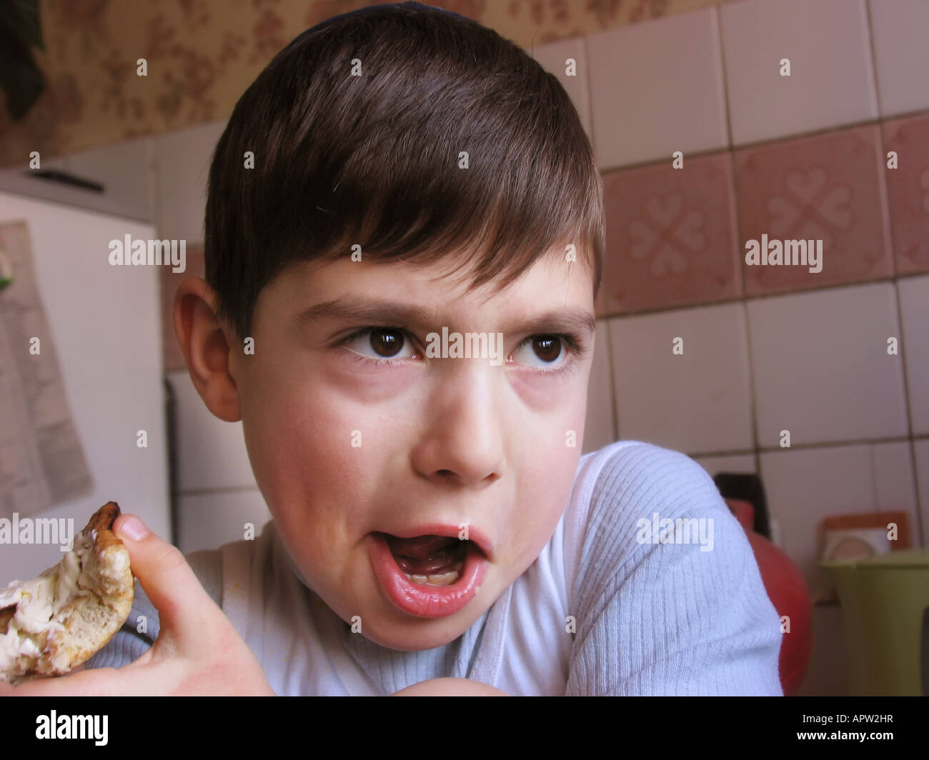8 years old boy eating near the window. Model released portrait Stock