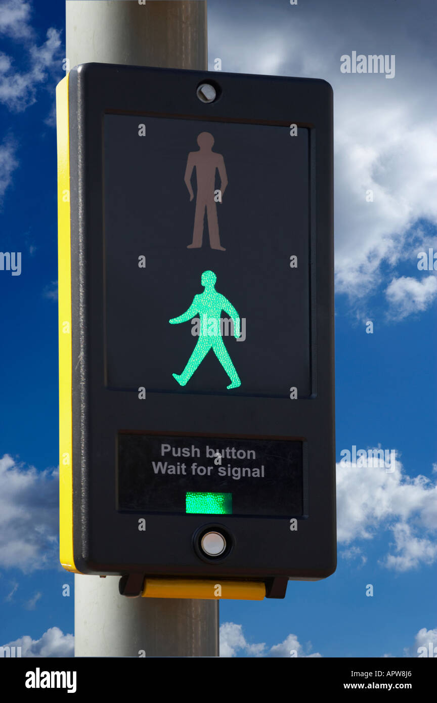 PEDESTRIAN CROSSING CONTROL BOX WITH ILLUMINATED GREEN MAN ICON AND BLUE SKY Stock Photo