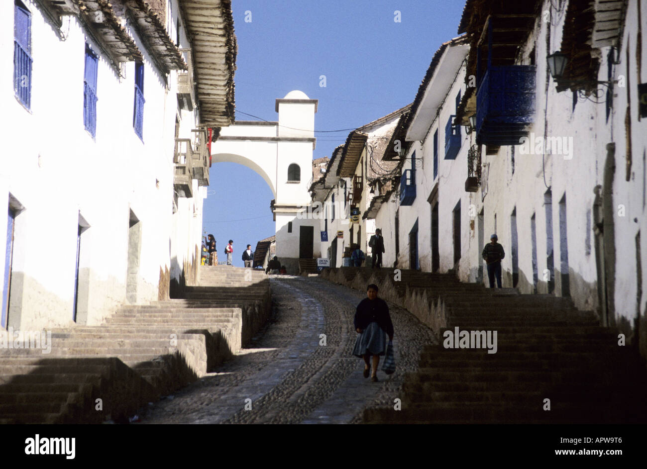 Old Spanish houses with white walls line a steep street in Cuzco, Peru