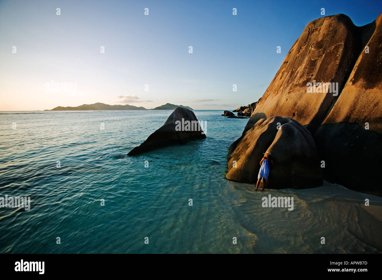 Woman relaxing on granite boulders of beach Model released Anse Source d Argent beach La Digue Island Seychelles Stock Photo