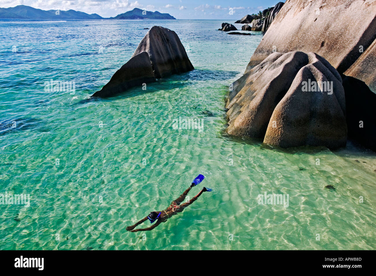 Woman snorkling in clear water amongst granite boulders Model released Anse Source d Argent beach La Digue Island Seychelles Stock Photo