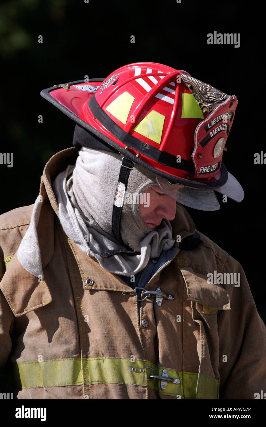 An American Lieutenant Firefighter for the city of Mequon Wisconsin looking down wearing a red helmet Stock Photo