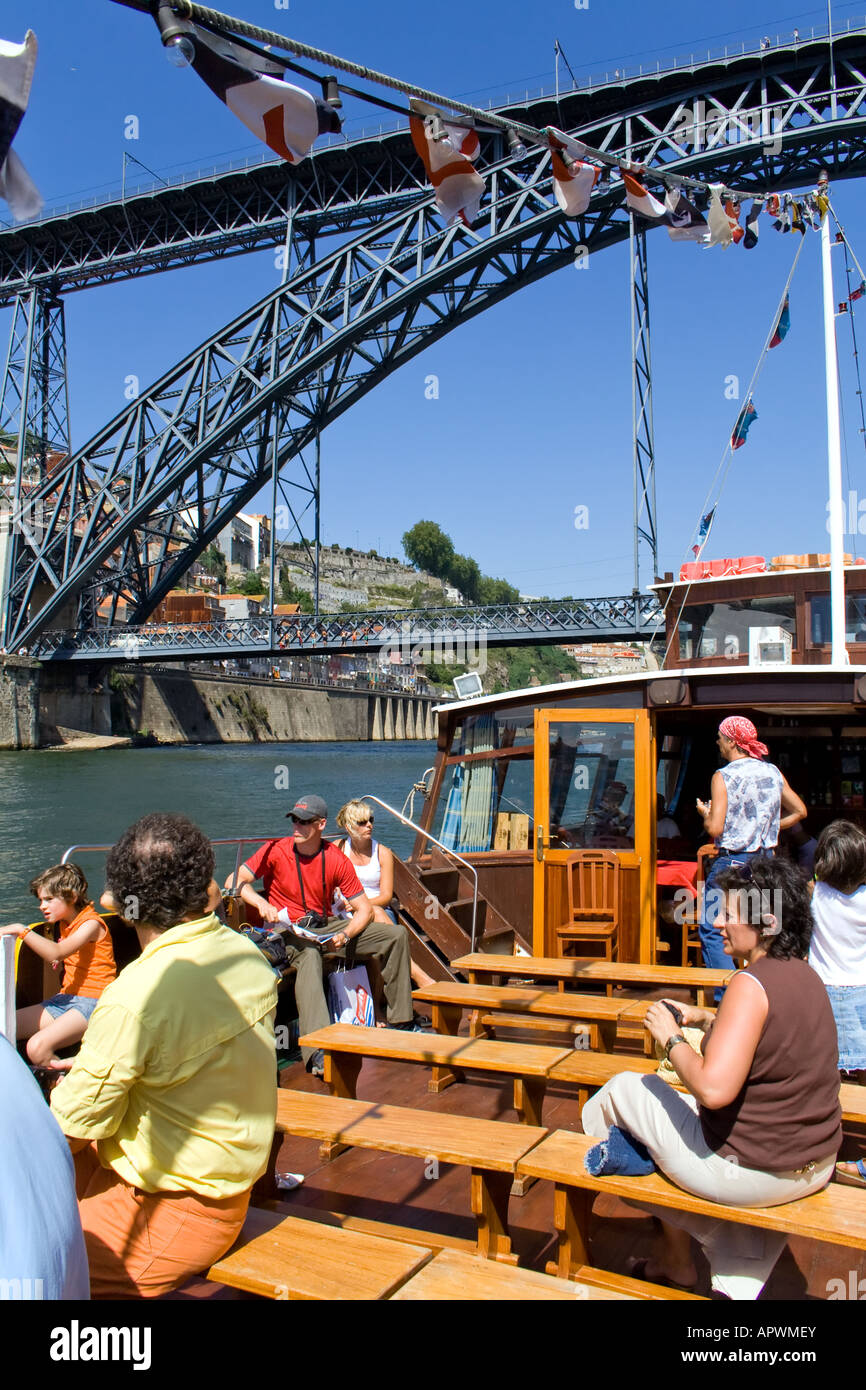Cruise in the Douro River at Porto (Portugal) using an adapted Rabelo Boat. D. Luiz I bridge seen in back. Stock Photo