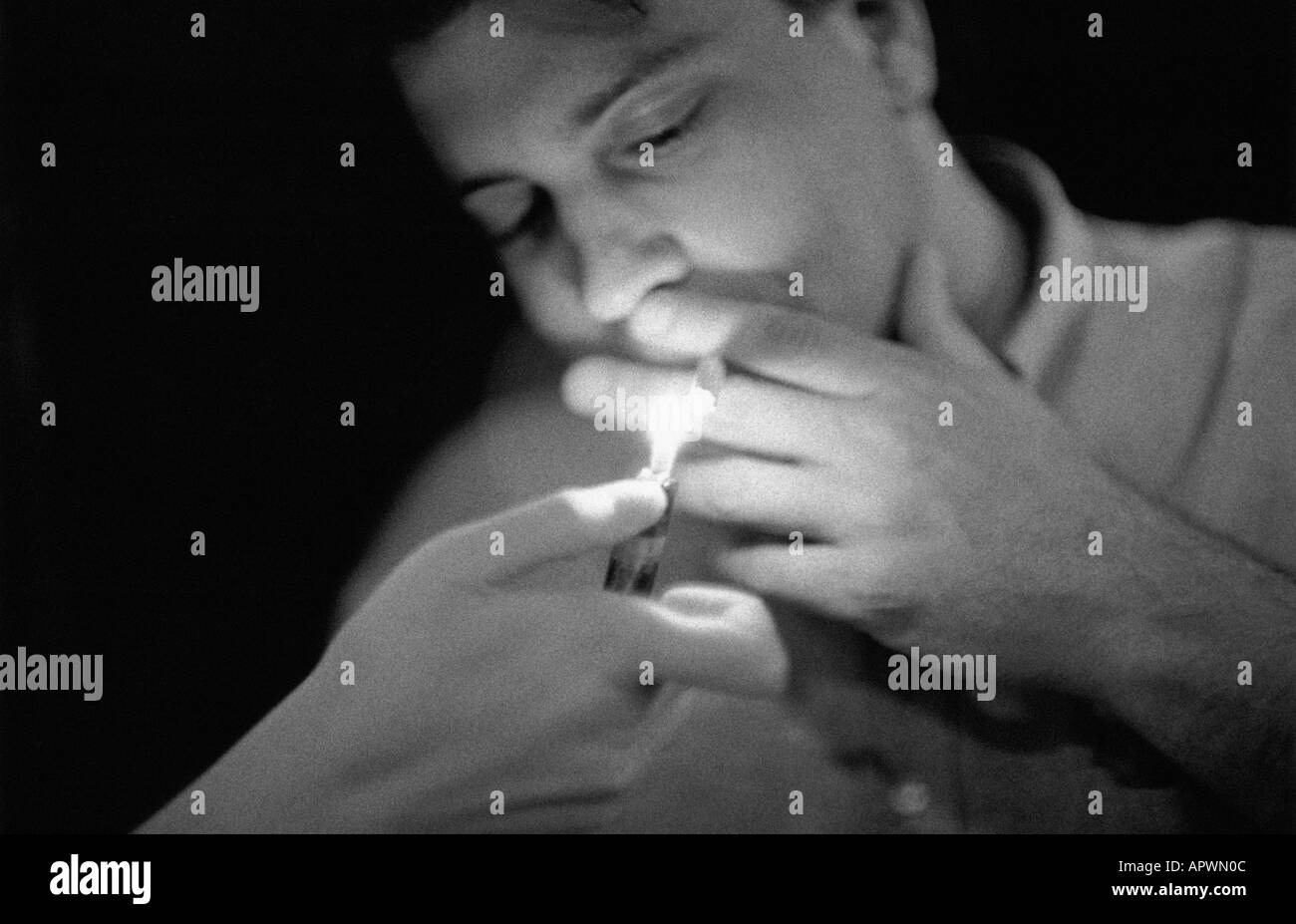 Young man lighting cigarette Black and White Stock Photos & Images Alamy
