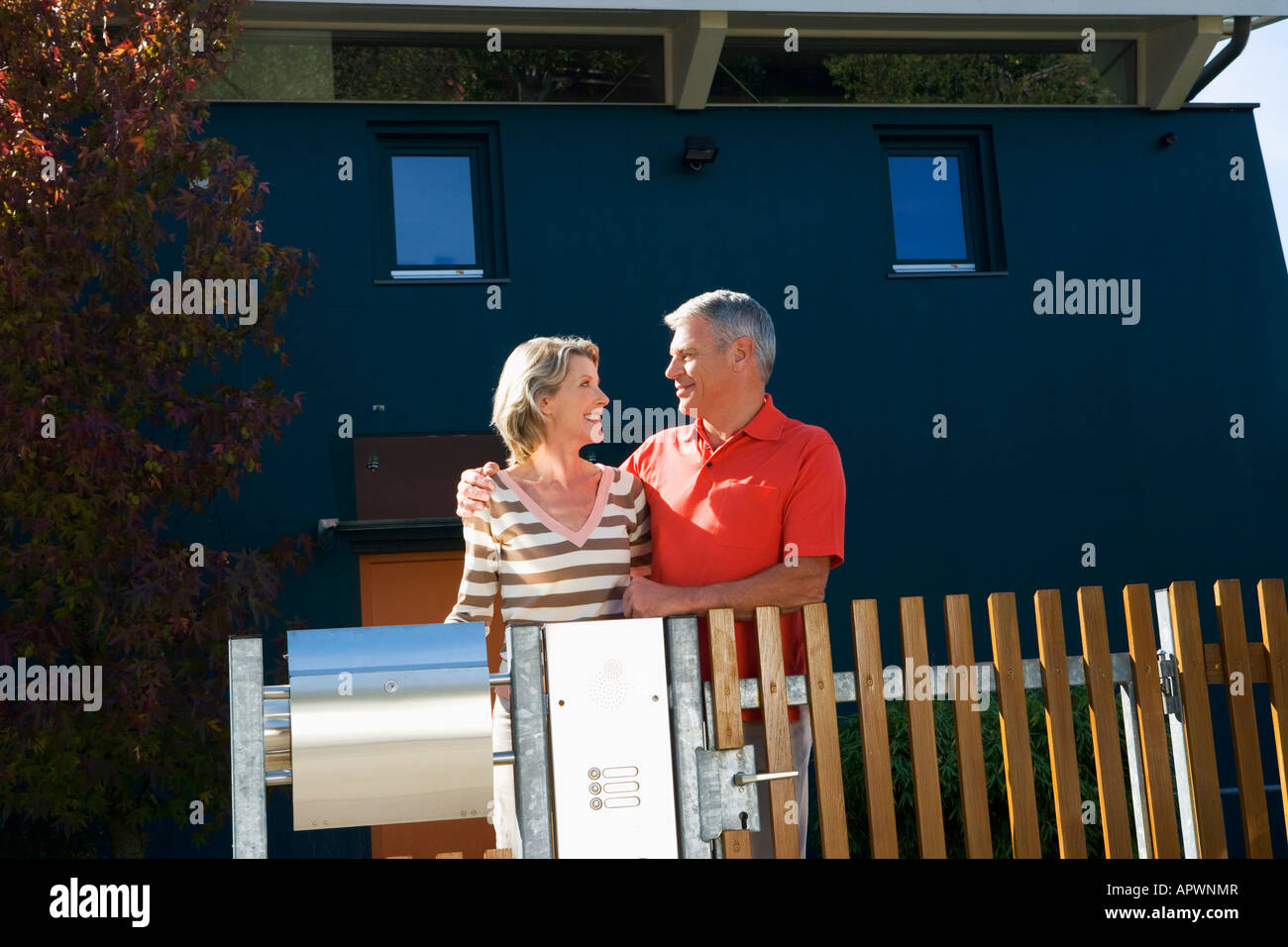 portrait of mature couple standing at garden fence of their home Stock ...