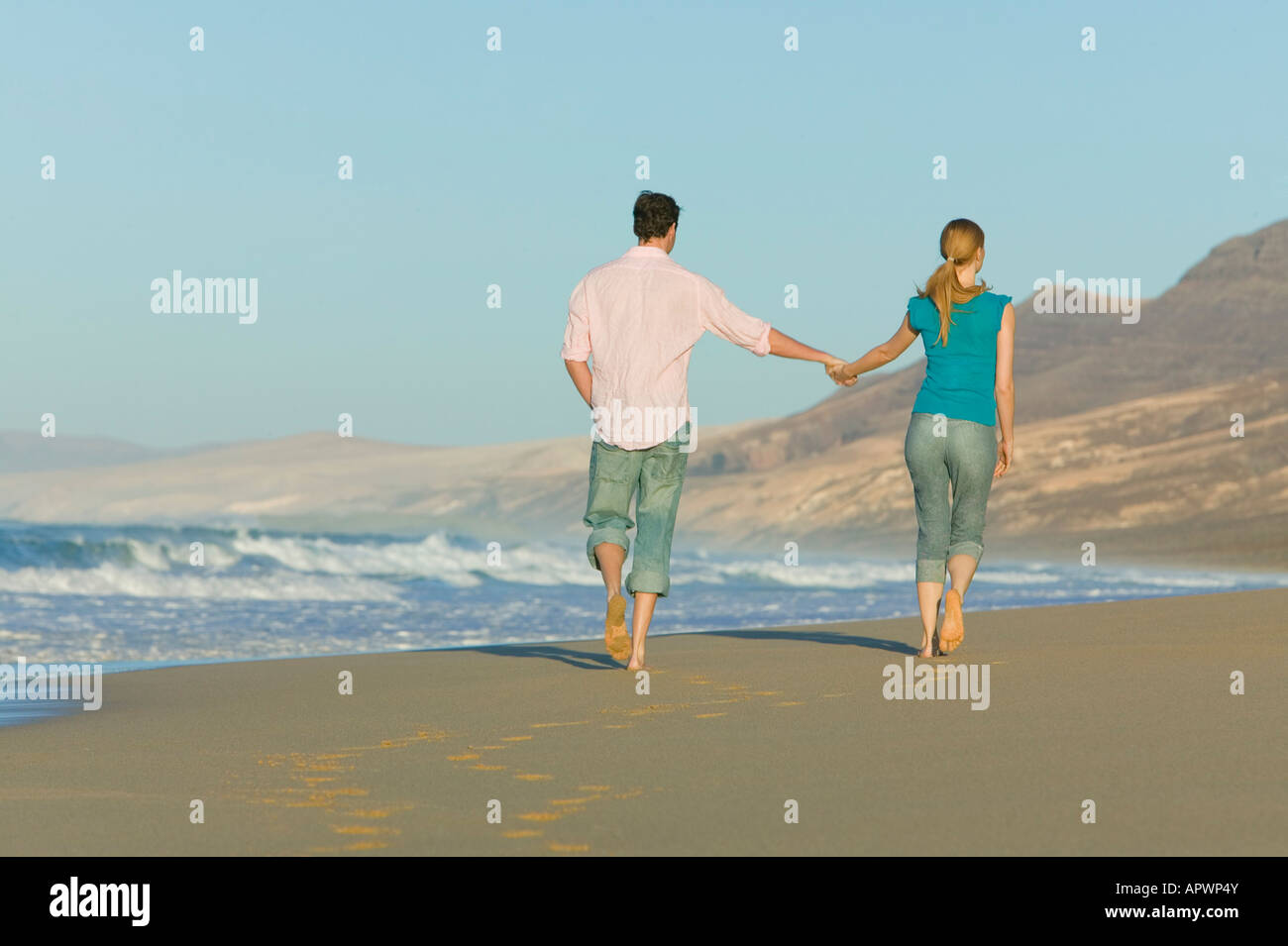 young couple walking along beach together Stock Photo - Alamy