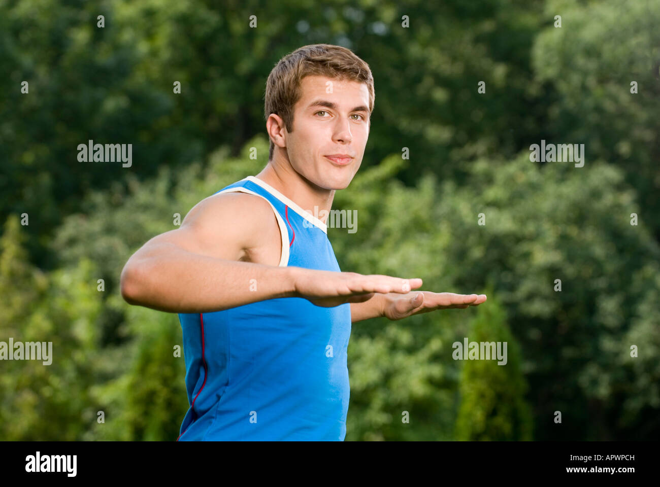 portrait of young man doing stretching exercise in park Stock Photo - Alamy