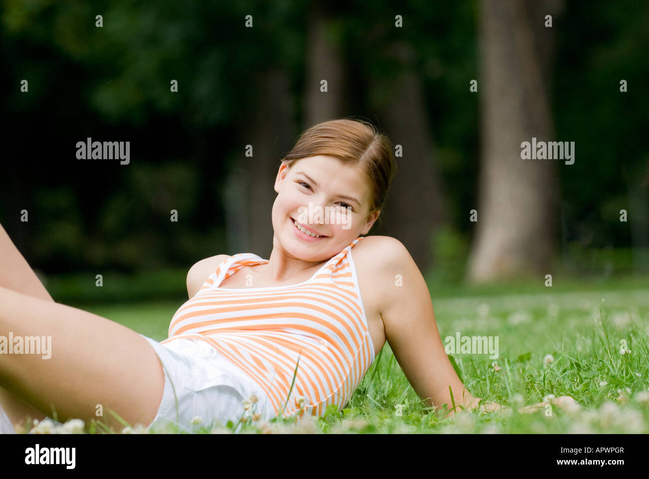 portrait of smiling young woman lying on lawn in park Stock Photo - Alamy