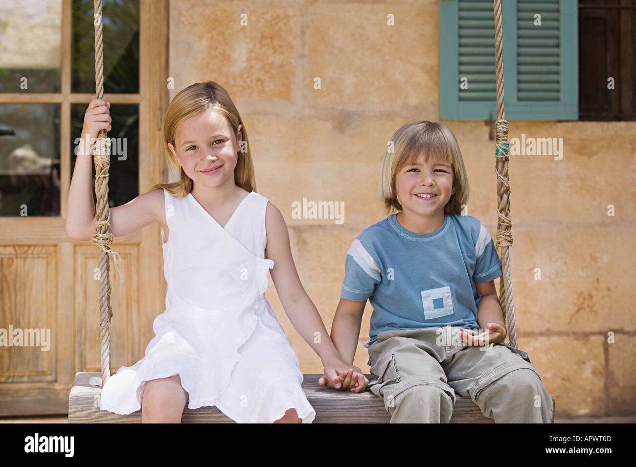 Brother and sister sitting on a swing Stock Photo - Alamy