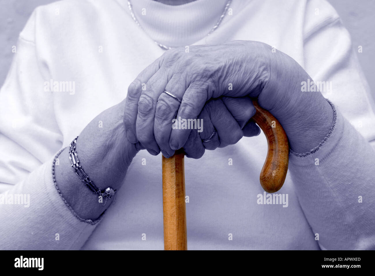 Octagenarian lady. Hands rest on walking stick. Elderly. Hypothermia Stock Photo