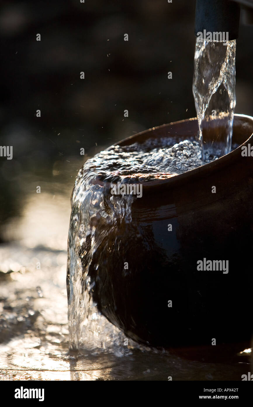Filling an Indian Clay pot with fresh clean water at a hand water Stock