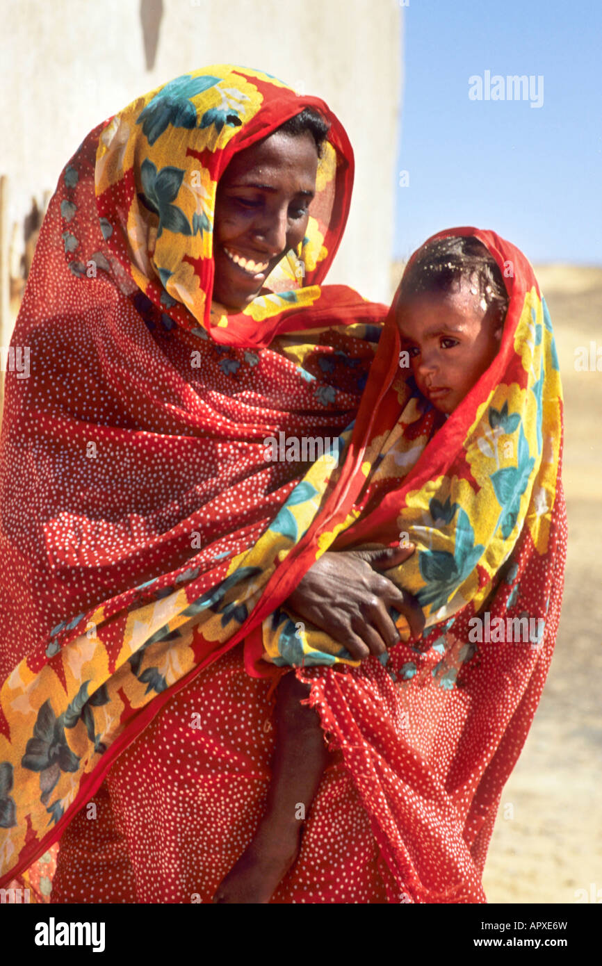 A young mother holding her child in the protective covering of her red cloak Stock Photo