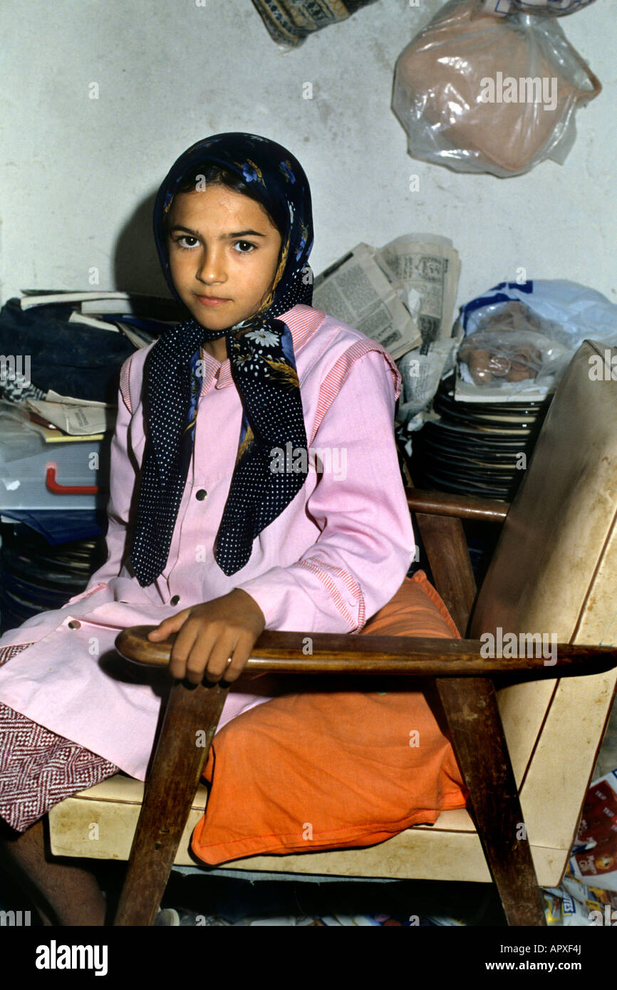 Young Tunisian girl seated in a chair wearing a headscarf and a pink tunic Stock Photo