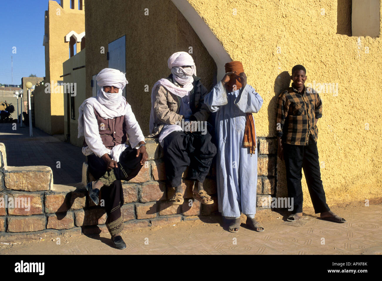 Group of Tuareg men sitting on a low wall in Illizi Stock Photo